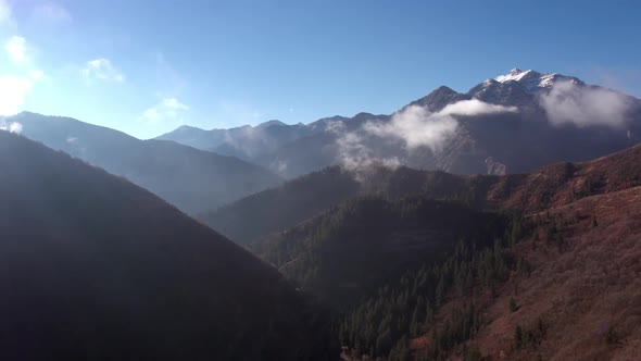 Aerial panning view of mountain layers with thin low clouds