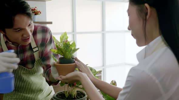 Young couple planting in the flower pots on a counter in living room at home.