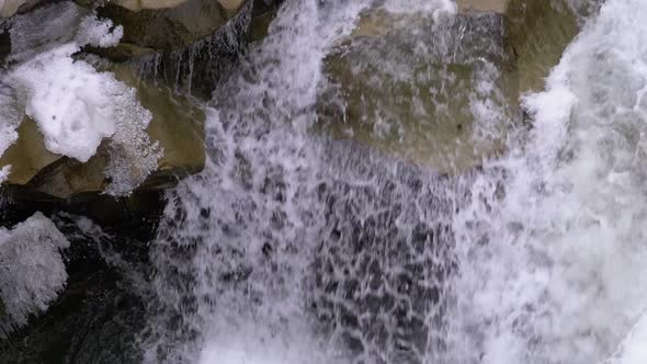 Mountain Creek and Stone Rapids with Snow. Rapid Flow of Water. Waterfall in the Winter. Slow Motion