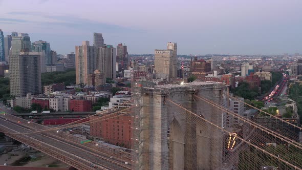 An aerial view of the Brooklyn Bridge at sunrise. The camera orbit the American flag on the bridge's