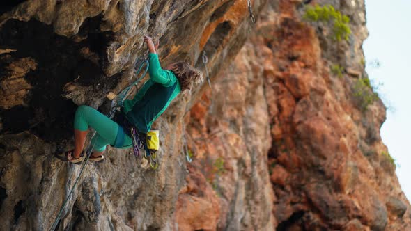 Strong Female Rock Climber Climbs Up Hard Tough Challenging Rock Route on Overhanging Black Crag