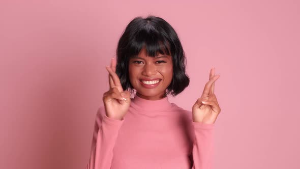 Positive Dark Skinned Woman Looks Up Crossing Her Fingers and Hopes for Good Luck