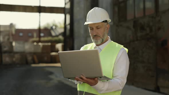 Man Working on Laptop While Standing at Outside Construction