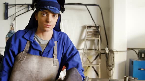 Welder standing with arm crossed in workshop