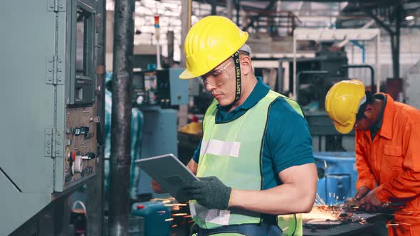 Group of Factory Workers Using Machine Equipment in Factory Workshop