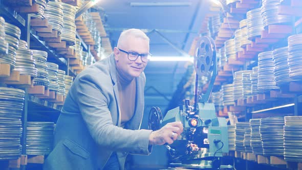 Film Expert is Smiling While Regulating Vintage Tape Projector