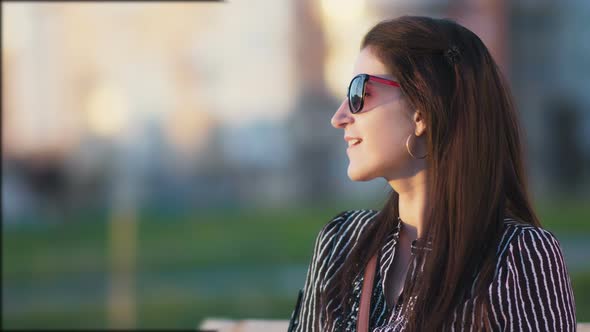 Charming Woman Relaxing and Enjoying the Sun in a Park at Sunset