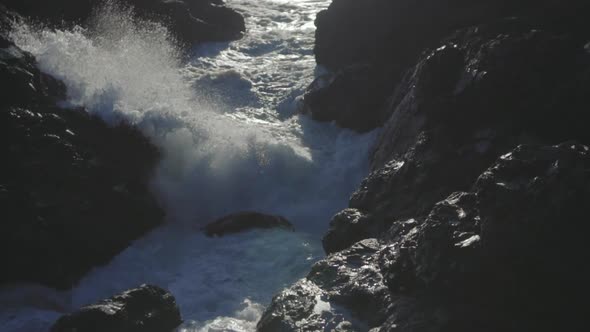 Slow motion close up shot of an ocean waves smashing on rocks and splashing around