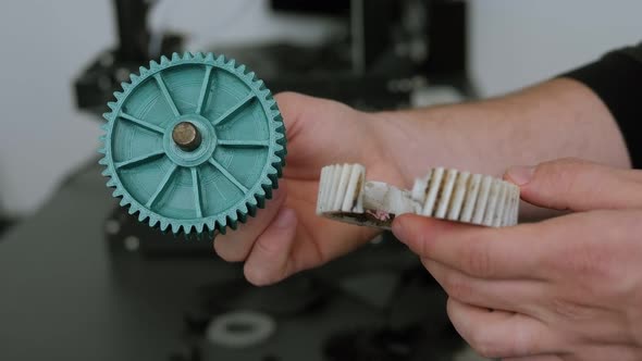 Close-up of a Male Engineer Demonstrates Plastic Models Printed on a 3D Printer.