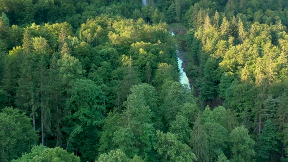 Drone flight over a stunning alpine mountain water fall. The water falls cascade down through the al