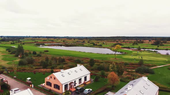 Aerial Outdoor View of a Beautiful Calm Rich Landscape with Big Modern Houses People Playing Golf