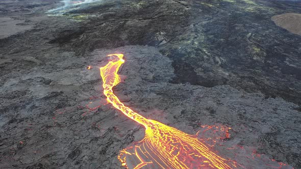 Iceland. Volcano eruption. Hot molten lava flowing from crater through lava streams on slope.