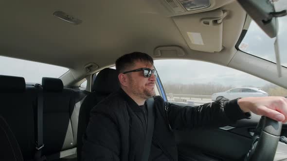 View of Man Driving Car in Day Time Hand on Steering Wheel