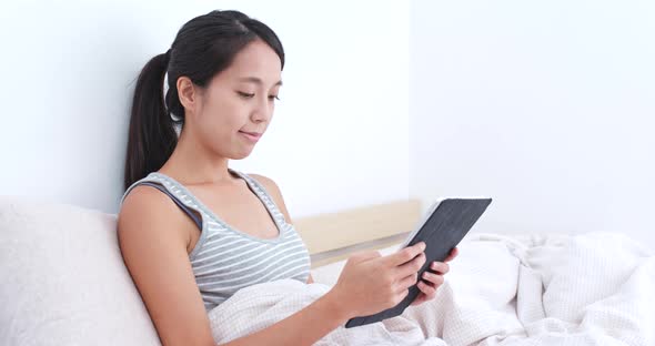 Woman watching tablet on bed