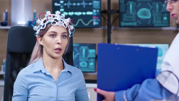 Female Patient Reading Brain Data From Clipboard Holded By Female Doctor