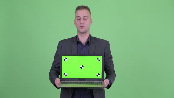 Happy Handsome Businessman in Suit Talking While Showing Laptop