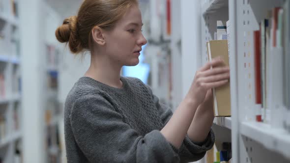 Redhead Woman Finding and Taking Book in Library