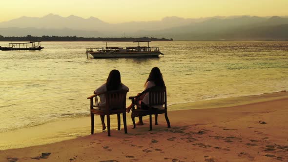 Women happy together on idyllic bay beach vacation by clear ocean with white sandy background of Gil