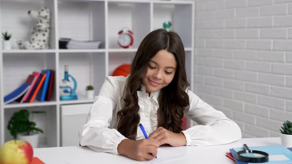 Concentrated Laughing Child in School Uniform Writing Homework Childhood Development