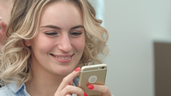 Woman having hair styling in salon while browsing the internet