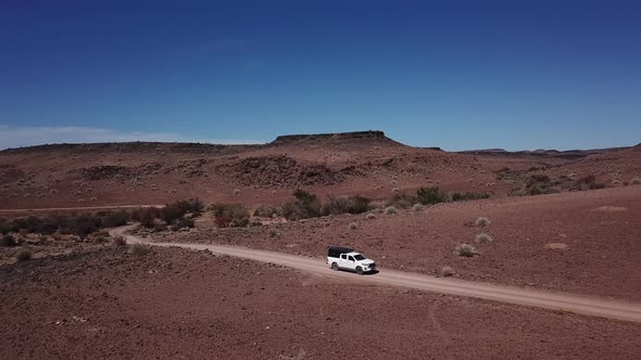 Car Driving on Gravel Road in Aerial Desert