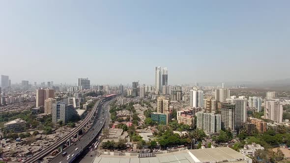 Skyline View of a City with skyscrapers, flyovers, metro railways and blue sky in a high angle shot.