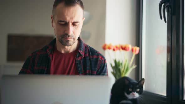 Handsome Middleaged Man Busy Typing on a Laptop While Working From Home