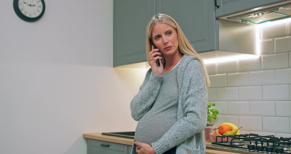 Young Pregnant Woman Talking to Her Husband Using Phone at Home