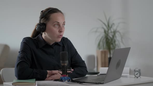 Young woman freelancer speaks into the microphone and records  Podcast