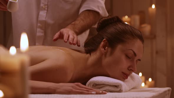 Massage Therapist Pouring Oil on Back of Woman in Spa Resort in Slowmotion