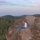 A Man Is Typing on a Laptop Sitting on the Edge of a Rocky Mountain. - VideoHive Item for Sale