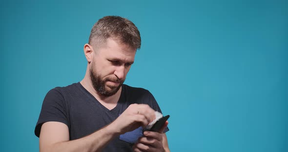 Serious Man with Beard Wipes Modern Smartphone Display