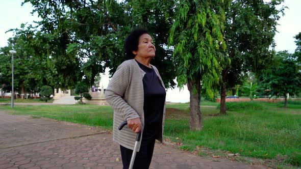 slow-motion of senior woman walking with walking stick in the park