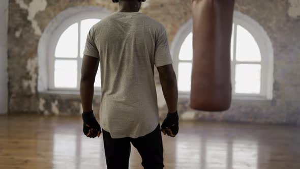 African American Athlete Walking Into Room with Boxing Pear with Wrapped Fists