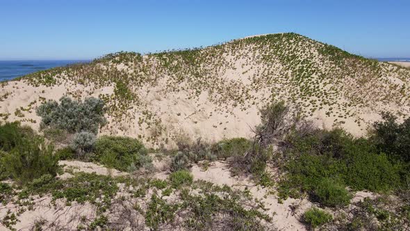 Cinematic Approach of Drone Flying Towards Sand Dune with Ocean in Horizon