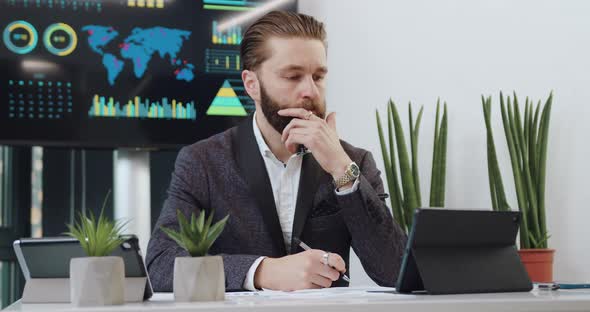 Hardworking Adult Bearded Office Manager Working at Tablet pc in His Office Room