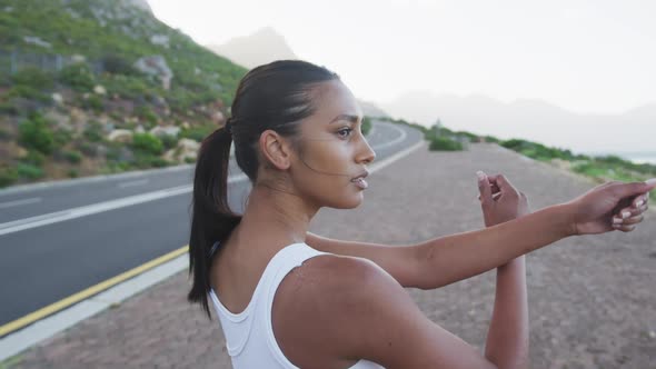 African american woman wearing sportswear performing stretching exercise on the road