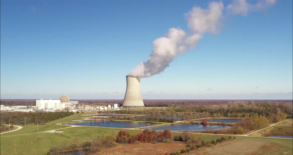 Nuclear power plant with steam coming out. Drone video pulling out.
