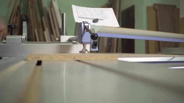 A man cuts a wooden slab on a format cutting machine