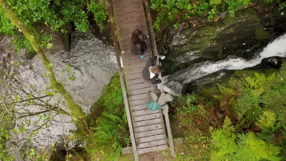 Overhead View Group of Tourists Walking Cinematic Wet Wooden Bridge Over River