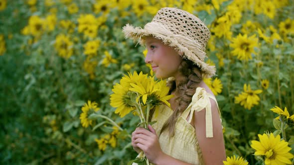 Pretty Smiling Girl in Hat Holding Bouquet of Sunflowers