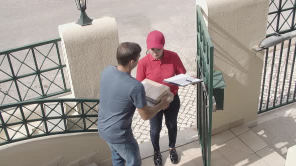 Courier Girl in Uniform Delivering Package To Customers Door