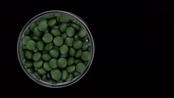 Green pills on black background. superfoods Spirulina, chlorella supplement green pills