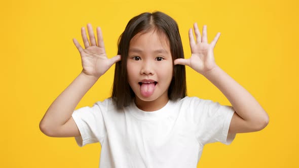 Funny Little Korean Girl Sticking Out Tongue Grimacing Yellow Background