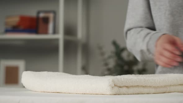 Young Woman Putting Washed Dry Clean Towels on Iron Board Preparing for Ironing