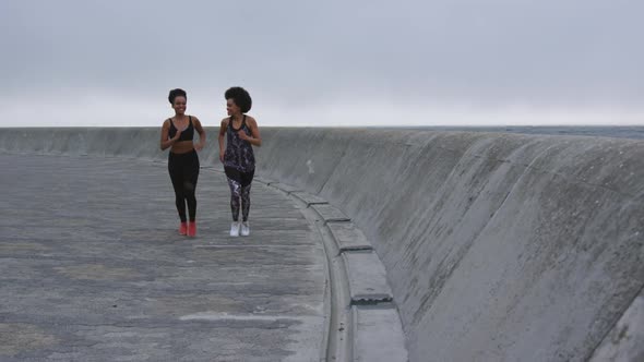 Two mixed race women running on docks