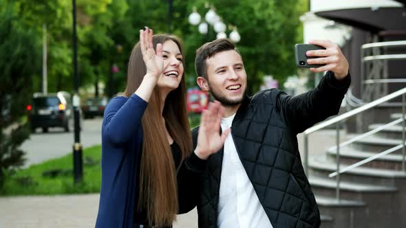 Happy Friends on the Street Having Video Chat with with Parents Via Smart Phone