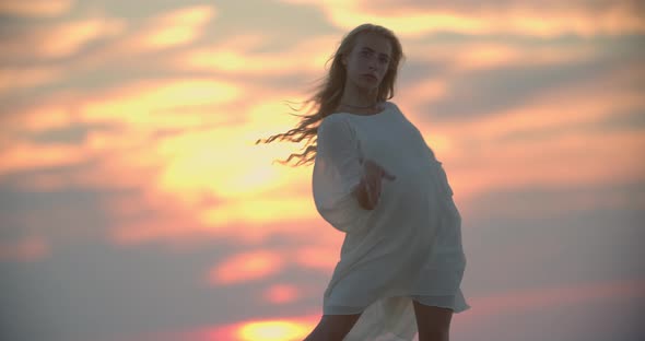 Gorgeous Sunset in the Background of a Young Woman Dancing in White Dress