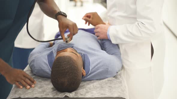 Patient Lying on a Gurney Doctor Makes Examination Listens to Breathing