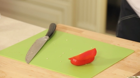 Cheff Is Slicing Red Paprika On a Cutting Board